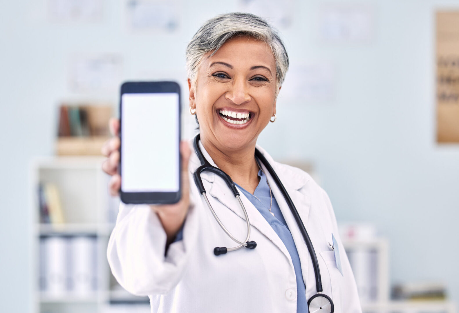 A woman in white lab coat holding up a phone.