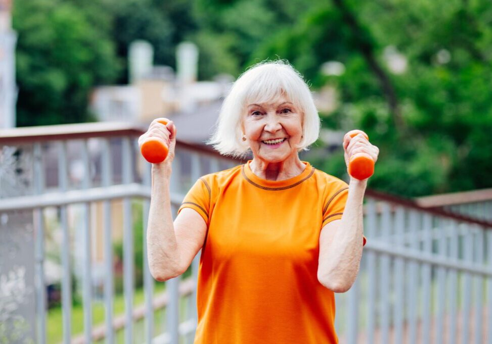 Beautiful sportive senior woman training outdoors - Mature adults old female doing fitness workout exercises in a park to stay healthy and fit
